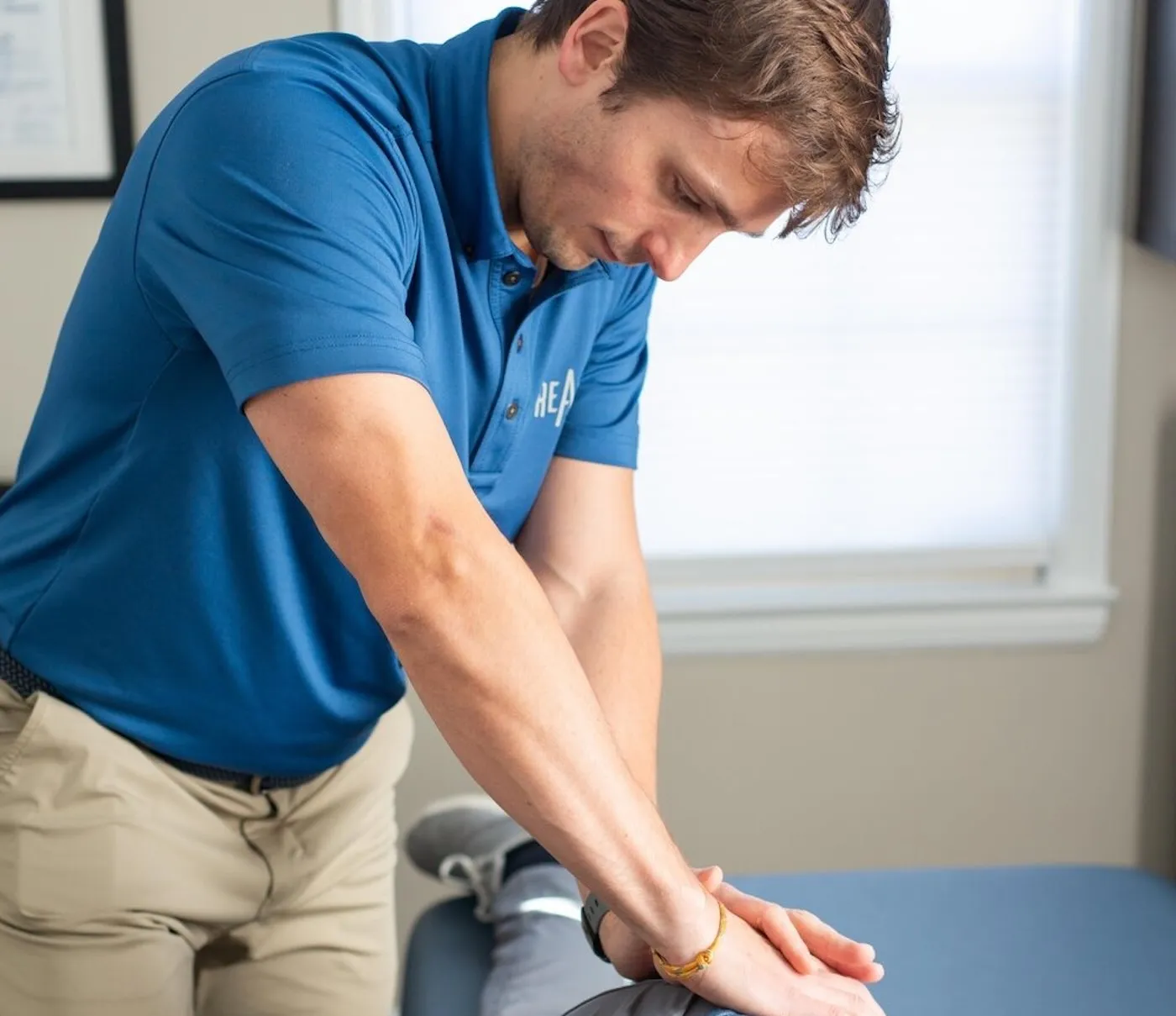 A REACH Rehab + Chiropractic clinician performing hands-on treatment on a patient's hip and leg