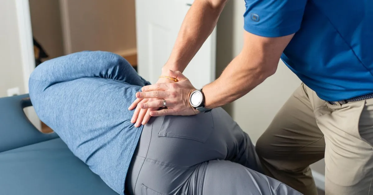 A REACH clinician pressing both hands into the hip and glute of a patient lying on their side on a treatment table