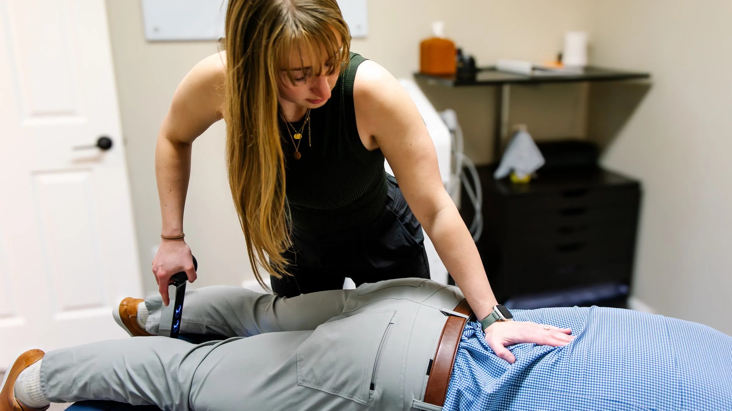 Dr. Sheridan Kent working the lever of a Cox flexion-distraction table with her other hand on the low back of a patient lying face down, at REACH Rehab + Chiropractic, Plymouth MI