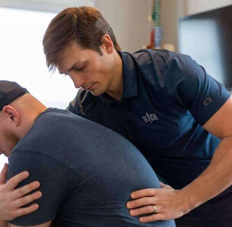 Chiropractor assessing a patient at REACH Rehab + Chiropractic in Plymouth, MI