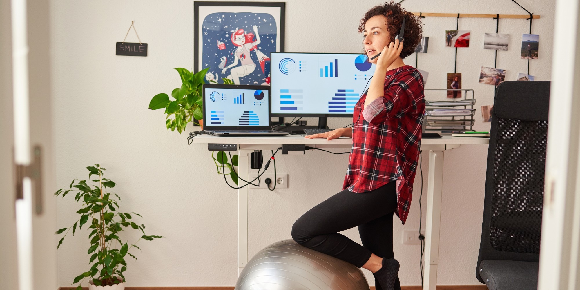 Woman Standing Next To An Ergonomic Workspace with an Exercise Ball and Standing Desk | How to Create an Ergonomic Workspace to Combat Headaches, Neck, and Back Pain | REACH Rehab +Chiropractic