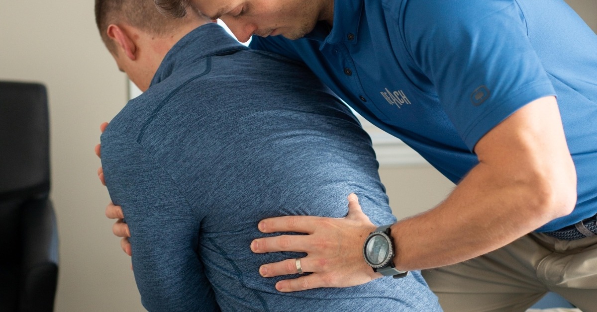 Chiropractor Helping a Patient With Back Pain | Chiropractic Solutions For Post-Surgery Back Pain Recovery | REACH Rehab + Chiropractic